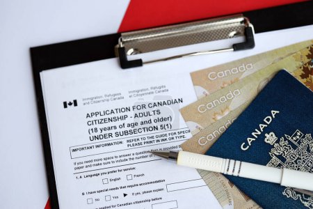 Téléchargez les photos : Demande de citoyenneté canadienne pour les adultes sur la table avec stylo, passeport et billets en dollars fermeture - en image libre de droit