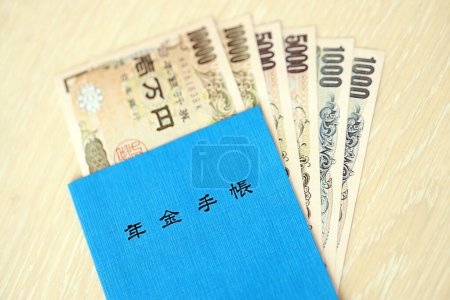 Foto de Libro de seguro de pensiones japonés en la mesa con billetes de yenes. Libro azul para los pensionistas japoneses de cerca - Imagen libre de derechos