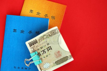 Foto de Folletos del seguro de pensiones japonés en la mesa con billetes de yenes. Primeros planos de libros azules y naranjas para pensionistas japoneses - Imagen libre de derechos