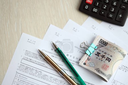 Japanische Steuerformulare liegen mit Taschenrechner, Stift und japanischen Yen auf dem Tisch