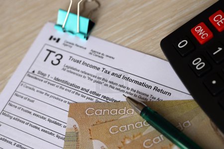 Canadian T3 tax form Trust income tax and information return liegt auf dem Tisch mit kanadischen Geldscheinen in Großaufnahme. Besteuerung und jährliche Buchhaltung in Kanada