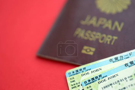 Téléchargez les photos : Carte de séjour verte du Japon avec passeport sur fond rouge close up - en image libre de droit