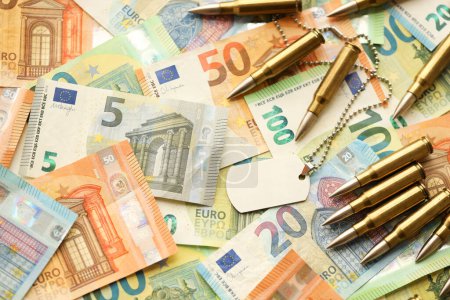 Gelbe Patronen und Hüllen auf Euro-Banknoten. Viele Scheine der Währung der Europäischen Union und Munition aus nächster Nähe