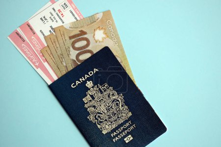 Kanadischer Pass mit Geld und Flugtickets auf blauem Hintergrund in Großaufnahme. Tourismus- und Reisekonzept