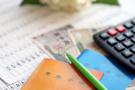 Foto de Folletos de seguros de pensiones japoneses en la mesa con billetes de yenes y calculadora en la mesa de primer plano - Imagen libre de derechos