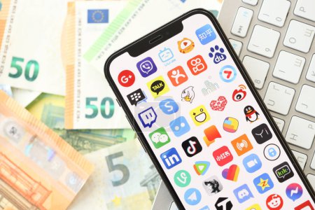 Photo for KYIV, UKRAINE - APRIL 1, 2024 Many apps icon on smartphone screen on many euro money bills. iPhone display with app logo with european currency euro banknotes and white keyboard - Royalty Free Image