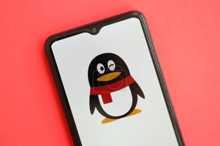Téléchargez les photos : KYIV, UKRAINE - 1 AVRIL 2024 Tencent icône QQ sur l'écran du smartphone sur la table rouge fermer. Écran iPhone avec logo app sur fond rouge vif - en image libre de droit