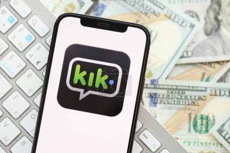 Photo for KYIV, UKRAINE - APRIL 1, 2024 Kik messenger icon on smartphone screen on many usd money bills. iPhone display with app logo and dollar banknotes with white keyboard - Royalty Free Image