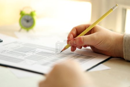 Téléchargez les photos : Étudiante test des mains en exercice et de prendre remplir une feuille de papier d'examen avec crayon à la salle de test de l'école, concept d'éducation - en image libre de droit