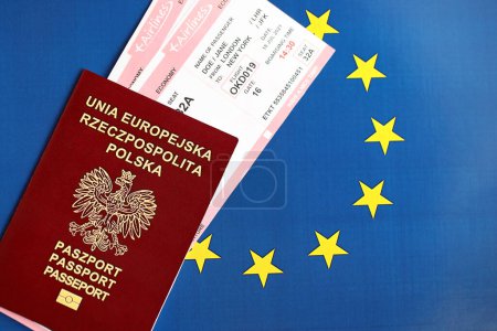Poland passport of European Union and airlines tickets on blue flag background close up. Tourism and travel concept