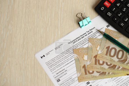 Kanadische T2-Steuerformular Körperschaftssteuererklärung liegt auf dem Tisch mit kanadischen Geldscheinen in Großaufnahme. Besteuerung und jährliche Buchhaltung in Kanada