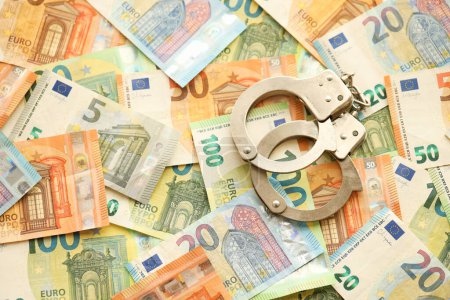 Many European euro money bills and handcuffs. Lot of banknotes of European union currency and cuffs close up