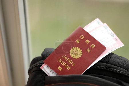 Pasaporte de Japón con billetes de avión en mochila turística de cerca. Concepto de turismo y viajes