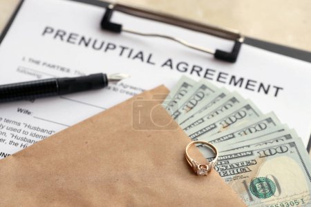 Prenuptial agreement and wedding ring on table. Premarital paperwork process in USA close up