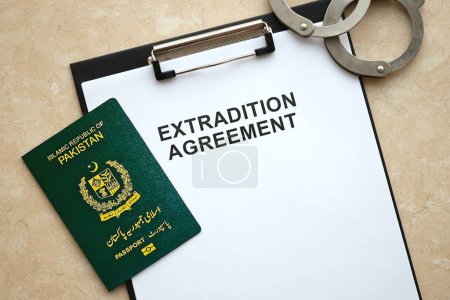 Passport of Pakistan and Extradition Agreement with handcuffs on table close up