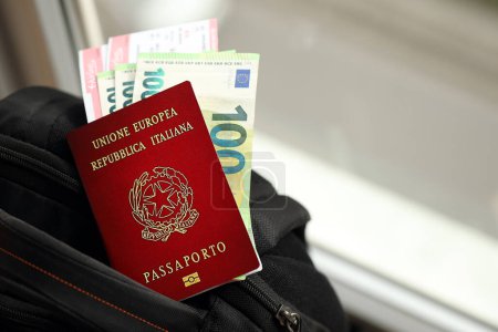 Pasaporte italiano y billetes de euro con billetes de avión en mochila de cerca