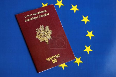French passport of European Union on blue flag background close up. Tourism and citizenship concept