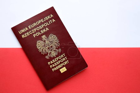Passeport rouge poli sur drapeau rouge et blanc lisse de la Pologne gros plan