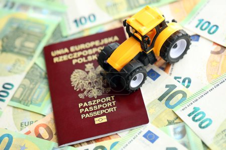 Passeport rouge poli et tracteur jaune sur les billets en euros fermer