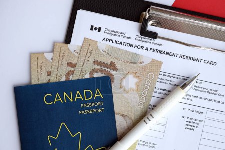 Antrag auf Daueraufenthaltskarte auf dem Tisch mit Stift und kanadischem Pass mit Geld aus nächster Nähe