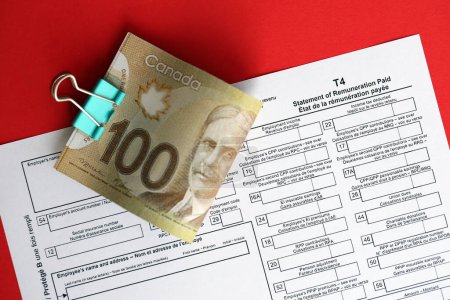 Das kanadische T4-Steuerformular Erklärung über die gezahlte Vergütung liegt auf dem Tisch, die kanadischen Geldscheine in Großaufnahme. Besteuerung und jährliche Buchhaltung in Kanada