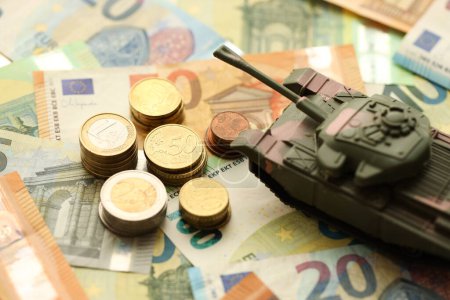 Viele Euro-Banknoten und Panzer. Viele Geldscheine der Europäischen Union und grüner Tank aus nächster Nähe