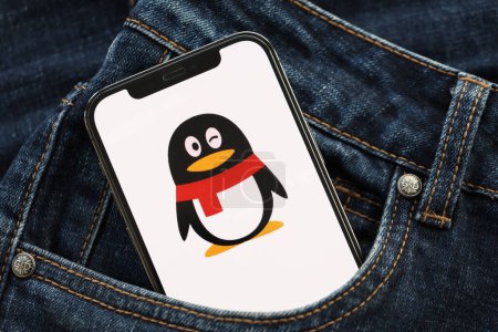 Téléchargez les photos : KYIV, UKRAINE - 1er AVRIL 2024 Tencent icône QQ sur l'écran du smartphone dans la poche du jean. Écran iPhone avec logo app cache dans la poche denims à la mode fermer - en image libre de droit