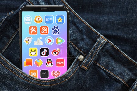Téléchargez les photos : KYIV, UKRAINE - 1 AVRIL 2024 icône des applications asiatiques sur l'écran d'affichage du smartphone dans la poche du jean. Écran iPhone avec logo app cache dans la poche denims à la mode fermer - en image libre de droit
