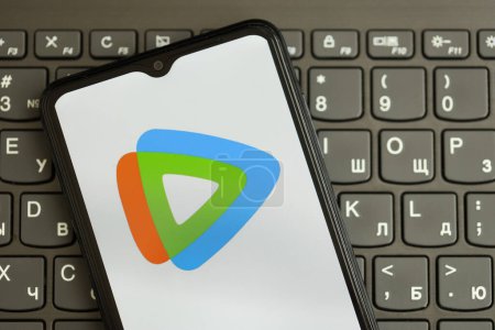 Téléchargez les photos : KYIV, UKRAINE - 1 AVRIL 2024 Tencent Video Icône WeTV sur l'écran du smartphone sur clavier noir fermer. Écran iPhone avec logo de l'application sur les boutons foncés du clavier - en image libre de droit
