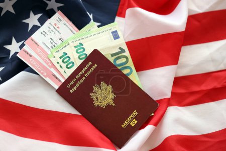 Pasaporte francés y dinero en euros con billetes de avión en el fondo de la bandera nacional de los Estados Unidos de cerca. Concepto de turismo y diplomacia