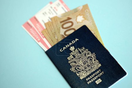 Kanadischer Pass mit Geld und Flugtickets auf blauem Hintergrund in Großaufnahme. Tourismus- und Reisekonzept