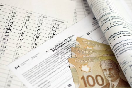 Canadian T2 tax form Corporation income tax return lies on table with canadian money bills close up. Taxation and annual accountant paperwork in Canada