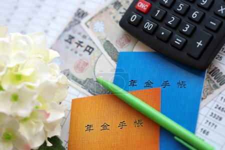 Japanische Broschüren zur Rentenversicherung auf dem Tisch mit Yen-Geldscheinen, Stift und Taschenrechner auf dem Tisch in Großaufnahme