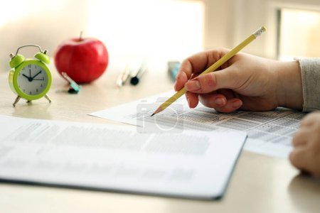 Téléchargez les photos : Étudiante test des mains en exercice et de prendre remplir une feuille de papier d'examen avec crayon à la salle de test de l'école, concept d'éducation - en image libre de droit