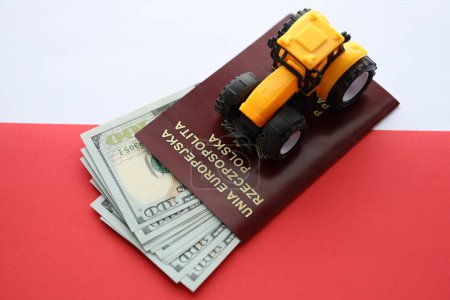 Passeport polonais rouge et tracteur jaune sur l'argent américain et drapeau rouge et blanc lisse de la Pologne gros plan