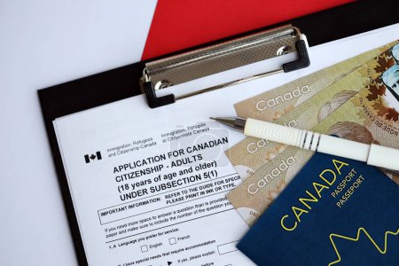 Photo for Application for Canadian citizenship for adults on table with pen, passport and dollar bills close up - Royalty Free Image