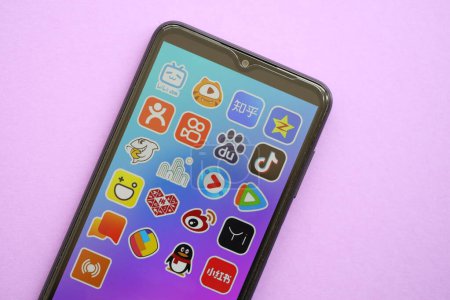 Téléchargez les photos : KYIV, UKRAINE - 1 AVRIL 2024 icône des applications asiatiques sur l'écran du smartphone sur la table violette fermer. Écran iPhone avec logo app sur fond lilas - en image libre de droit