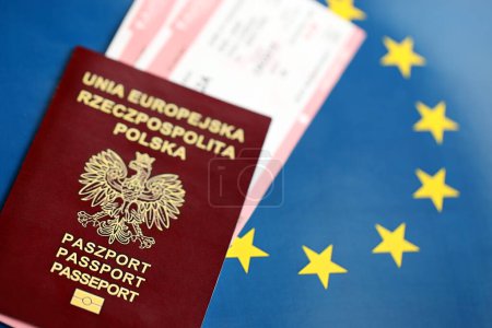 Poland passport of European Union and airlines tickets on blue flag background close up. Tourism and travel concept