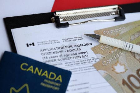 Solicitud de ciudadanía canadiense para adultos en la mesa con bolígrafo, pasaporte y billetes de dólar de cerca