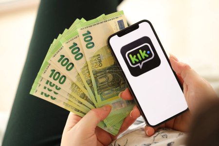 Photo for KYIV, UKRAINE - APRIL 1, 2024 Kik messenger icon on smartphone screen and money in female hand. iPhone display with app logo and hundred euro bills in girls hands close up - Royalty Free Image