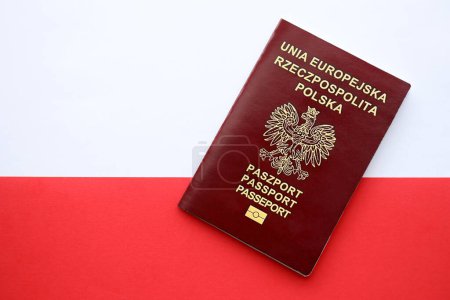Foto de Pasaporte rojo pulido sobre bandera lisa roja y blanca de Polonia - Imagen libre de derechos