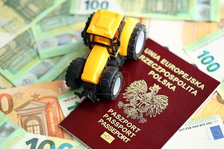 Pasaporte rojo polaco y tractor amarillo en billetes de euros de cerca