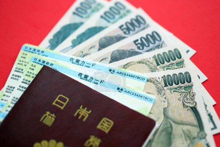 Téléchargez les photos : Carte de séjour verte du Japon avec passeport et argent du yen japonais sur fond rouge gros plan - en image libre de droit