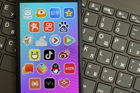 Téléchargez les photos : KYIV, UKRAINE - 1 AVRIL 2024 icône des applications asiatiques sur l'écran du smartphone sur clavier noir fermer. Écran iPhone avec logo de l'application sur les boutons foncés du clavier - en image libre de droit