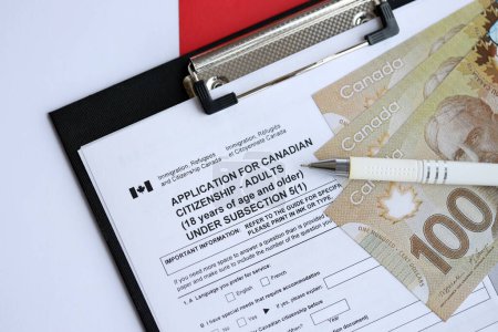 Téléchargez les photos : Demande de citoyenneté canadienne pour les adultes sur la table avec stylo et billets en dollars fermer - en image libre de droit