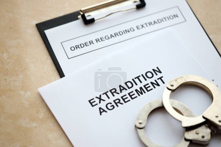 Auslieferungsabkommen und Auslieferungsverfügung mit Handschellen auf dem Tisch