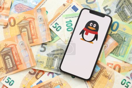 Téléchargez les photos : KYIV, UKRAINE - 1 AVRIL 2024 Tencent icône QQ sur l'écran du smartphone sur de nombreuses factures en euros. Ecran iPhone avec logo app avec monnaie européenne billets en euros - en image libre de droit