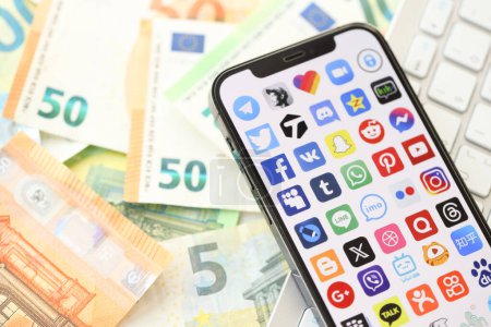 Photo for KYIV, UKRAINE - APRIL 1, 2024 Many apps icon on smartphone screen on many euro money bills. iPhone display with app logo with european currency euro banknotes and white keyboard - Royalty Free Image