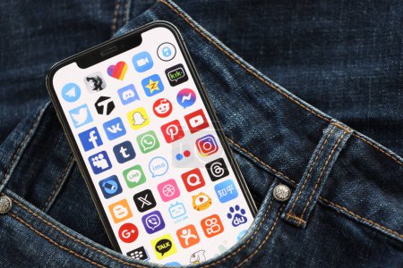 Photo for KYIV, UKRAINE - APRIL 1, 2024 Many apps icon on smartphone display screen in jeans pocket. iPhone display with app logo hide in fashionable denims pocket close up - Royalty Free Image