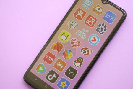 Téléchargez les photos : KYIV, UKRAINE - 1 AVRIL 2024 icône des applications asiatiques sur l'écran du smartphone sur la table violette fermer. Écran iPhone avec logo app sur fond lilas - en image libre de droit